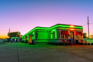 a green building with chairs in a parking lot at Boots Court Motel in Carthage