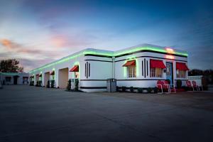 a gas station with red chairs in a parking lot at Boots Court Motel in Carthage