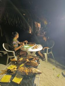 a woman sitting at a table with a plate of food at Ocean Sunset in Dhangethi