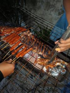 a bunch of sausages and bacon cooking on a grill at Ocean Sunset in Dhangethi