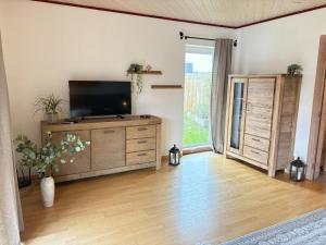 a living room with a television on a wooden dresser at Elkjer 24 in Großenwiehe