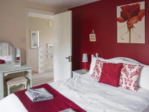 Schlafzimmer mit roten Wänden und einem Bett mit roten Kissen in der Unterkunft Ash Cottage E1224 in Winthorpe + 24 Fotos