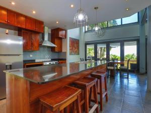 a kitchen with a long bar with wooden stools at Casa Cielo Luxury Jungle Retreat, Manuel Antonio in Quepos