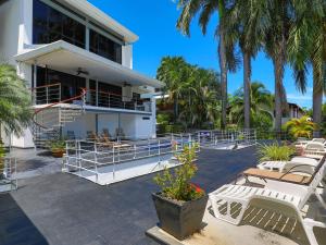 a white house with chairs and palm trees at Casa Cielo Luxury Jungle Retreat, Manuel Antonio in Quepos