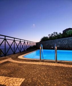 a swimming pool next to a brick wall with a bridge at Villa Ocean Wave Calheta - Heated Pool & Stunning Ocean View in Calheta +31 photos