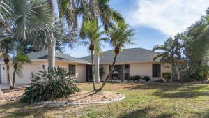 une maison avec des palmiers devant dans l'établissement Coral Key Escape w Waterfront Heated Pool-Spa-Direct Gulf Access, à Cape Coral