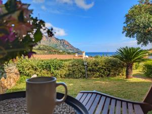 a coffee cup sitting on a table with a view of the ocean at Villa Sa Perla - Pool, Panoramic View, 250m to Seafront, 650m to Beach in Marina di Gairo