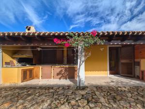 a house with a tree with pink flowers at Villa Sa Perla - Pool, Panoramic View, 250m to Seafront, 650m to Beach in Marina di Gairo