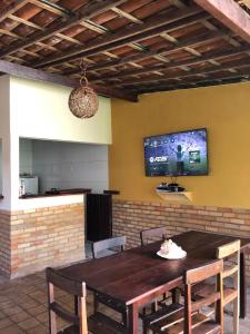 a dining room table with chairs and a tv on the wall at Pipa Villa Mar in Pipa