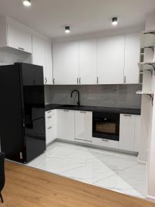 a kitchen with white cabinets and a black refrigerator at Mieszkanie 3 pokojowe Marki in Marki