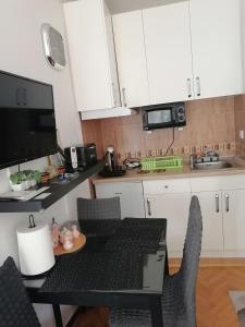 une cuisine avec des armoires blanches et une table et des chaises dans l'établissement Apartman Lala, à Vrnjačka Banja