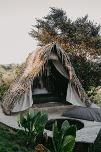 ein Bett in einem grasgedeckten Zelt auf einem Feld in der Unterkunft OYA New Earth Luxury Romantic Glamping with Private Outdoor Bath in Jamao al Norte