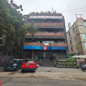 a building with cars parked in a parking lot at Bluestone Prime by The Cosy Hotels in New Delhi