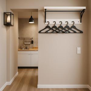 a kitchen with white cabinets and a wall with hangers at Apartments KR in Cologne