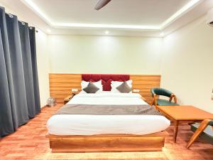 大诺伊达The Prominence Hotel Greater Noida的一间卧室，里面有一张大床和一张桌子。 更多29张照片