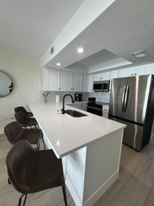 una cucina con bancone bianco e frigorifero di Irresistible Beach Life, Spectacular Sunsets - FMB - Condo Sunset Vista - Roelens a Fort Myers Beach