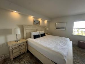 una camera con un grande letto bianco e un comodino di Irresistible Beach Life, Spectacular Sunsets - FMB - Condo Sunset Vista - Roelens a Fort Myers Beach