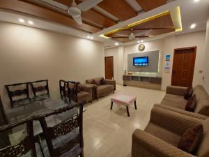 a living room with couches and a flat screen tv at The Oak Residence in Islamabad