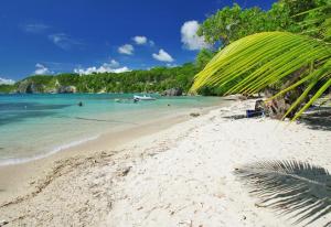 a sandy beach with a boat in the water at Kreyol Chic in Le Gosier