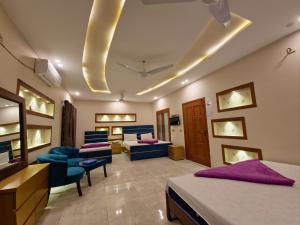 a hotel room with two beds and blue chairs at The Oak Residence in Islamabad