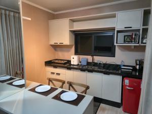 cocina con armarios blancos y nevera roja en Casa Container Oceano, en Foz do Iguaçu