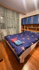a bedroom with a bed with a blue comforter and shelves at Charming Vintage Apartment 5 min to City Center Self Check-in in Craiova