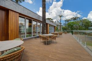 un patio al aire libre con mesas, sillas y ventanas en Vêneto Luxo 1 dorm Achei Gramado, en Gramado