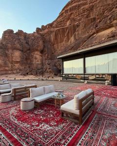 uma sala de estar com sofás e uma parede de pedra em Desert Pearl Luxury Camp em Wadi Rum mais 116 fotografias