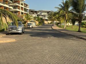 une voiture garée dans une rue avec des palmiers dans l'établissement Waterfront - B luxury, à Dakar