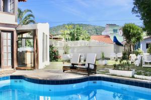 a house with a swimming pool and two chairs at Pousada Kaianoá in Arraial do Cabo