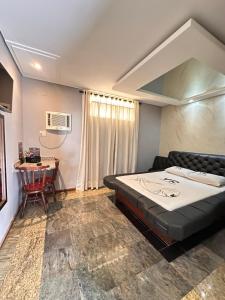 Motel Vitoria Reggia في ساو فيسينتي: غرفة نوم بها سرير كبير وطاولة