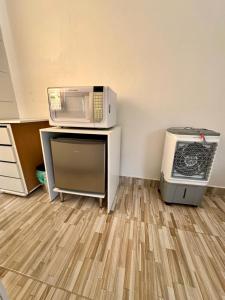 Eine Mikrowelle steht auf einem Schreibtisch neben einem Kühlschrank. in der Unterkunft Apartamento 01 Vila Telebrasília in Brasilia