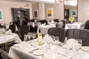 a dining room with tables and chairs with white table linen at Óstán Loch Altan in Cashel Hill