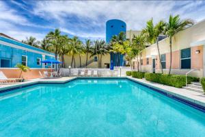 a swimming pool in front of a building with palm trees at Exclusive Studio Steps To The Beach With Pool in Hollywood Beach