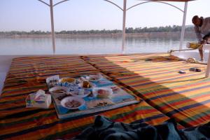 a table with a tray of food on the water at Gana kato in Aswan