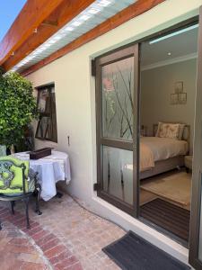 Un patio con puerta de cristal, una cama y una mesa. en Shire Lodge, en Ciudad del Cabo