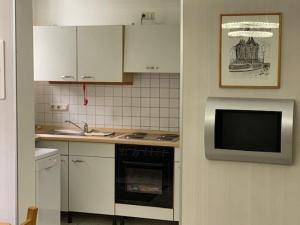 La cuisine est équipée de placards blancs, d'une cuisinière et d'un four micro-ondes. dans l'établissement Wohnung In Dreveskirchen Mit Kleinem Garten, à Blowatz