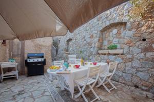 a table and chairs in a patio with a stone wall at Casa Lisa - appartement dans le village de Monticello vue mer in Monticello