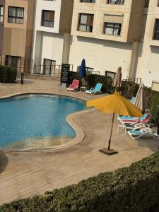 a pool with chairs and an umbrella next to a building at Unique duplex hotel apartment pool view in Cairo