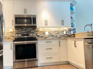 eine Küche mit weißen Schränken und Geräten aus Edelstahl in der Unterkunft Tanglewood 13 in Parksville