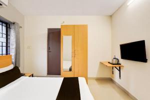 una camera d'albergo con un letto e una televisione di Super Townhouse Nanganallur Near Chennai Airport a Chennai