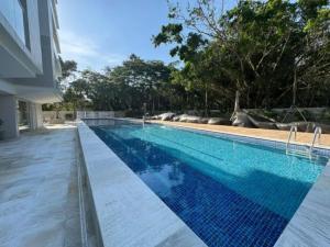 une piscine à l'eau bleue dans un immeuble dans l'établissement Apartamento Novo em São Lourenço, à Bertioga