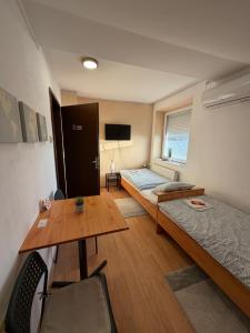 a room with two beds and a table and a desk at Sobe Zoka in Subotica
