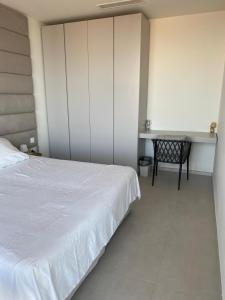 a bedroom with a white bed and a desk at Mercury tower Elena K 24th panoramic view apartment in St Julian's +11 photos