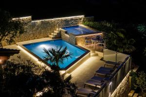 einen Pool in der Nacht mit einem Tisch und Stühlen in der Unterkunft Ferienhaus in Ražanj mit Großem Garten in Ražanj