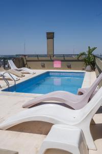 a pool with lounge chairs next to a building at The Point Casa Edificio Boutique in San Miguel de Tucumán