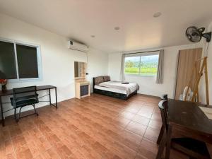 a bedroom with a bed and a desk and window at Sandy house Pai 2 in Pai