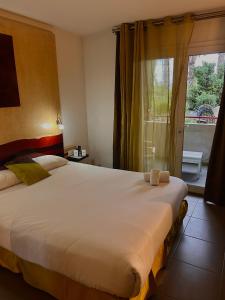 a bedroom with a large white bed and a window at Logis Hôtel La Fauceille in Perpignan