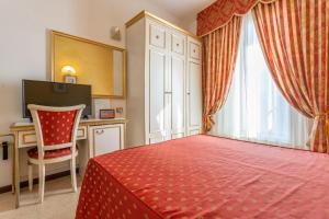 a bedroom with a red bed and a desk and a window at Hotel King in Rimini +25 photos