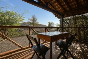 a wooden table and two chairs on a deck at Pousada A Mata que Canta in Socorro